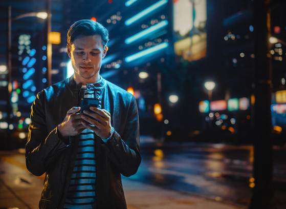 Man in the city looking at his phone at night